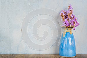 Pink flower in blue vase on a wooden table