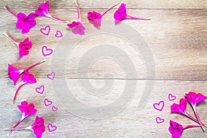 Pink flowers formed as border with hearts on vintage grunge wooden background
