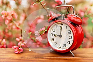 Pink flowers and retro alarm clock, spring or daylight savings time background