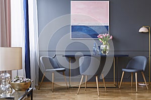 Pink flowers on table in dining room interior with painting and