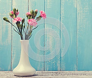 Pink flowers in a vase on blue background
