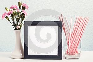 Pink flowers in a vase, paper straws and blank frame