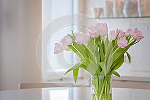 Pink flowers white kitchen. Valentine\'s day home. Clean home office, tulips for Women`s Day celebration. Scandinavian Nordic