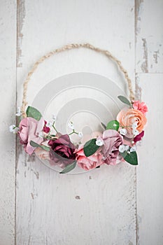 Pink flowers wraith or tiara on white wooden background