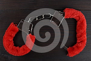 pink fluffy handcuffs on a wooden background. Valentine& x27;s Day