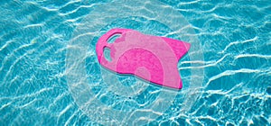 Pink foam board floating on swimming pool.