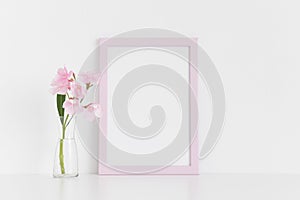 Pink frame mockup with pink oleander in a glass vase on a white table.Portrait orientation