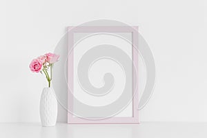 Pink frame mockup with pink roses in a vase on a white table.Portrait orientation