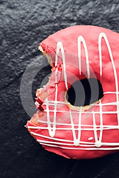 Pink frosted donut on dark background