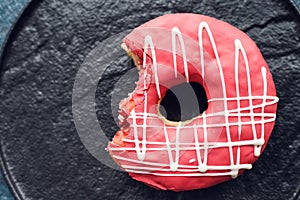 Pink frosted donut on dark background