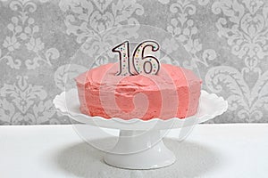 Pink frosted layer cake with the number 16 on top