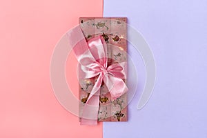 pink fruit chocolate with raisins and nuts on lilac and pink color background Dessert Time concept Flat lay Top view Candy shop