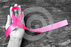 Pink fuchsia ribbon on woman`s hand isolated with clipping path for raising Breast cancer awareness and women`s health campaign