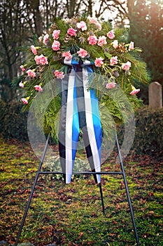 Pink funeral flower wreath on the cemetery. Vertical image.