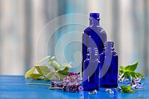 Pink geranium flower with an aromatherapy essential oil blue glass dropper bottle, over ble blured background