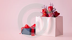 Pink gift bag with rose bouquet and black gift box on pink background