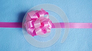 Pink gift bow on blue fabric background
