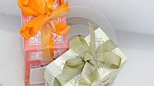 Pink gift box near the green box with bows