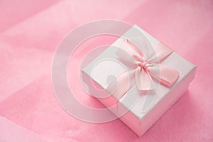 Pink gift box with ribbon bow on pink craft background. Craft pink paper gift box with as a present for Christmas, new year,