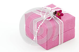 Pink gift box with a ribbon and a little flower