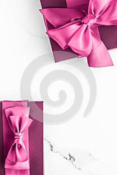 Pink gift box with silk bow on marble background, girl baby shower present and glamour fashion gift for luxury beauty brand,