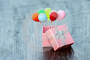 Pink gift box with silver ribbon and colorful balloon on wooden background. minimal hollyday concept