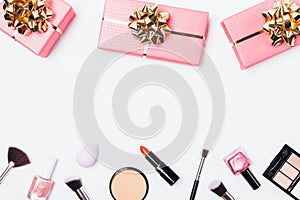 Pink gift boxes with golden bows near makeup products