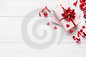 Pink gift boxes with red ribbons and bows, confetti hearts on a white background. Copy space Flat lay. Greeting card for