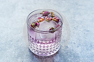 Pink Gin Tonic Cocktail with Dried Rose Buds and Ice in Glass Cup