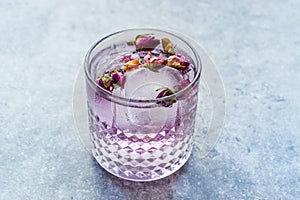 Pink Gin Tonic Cocktail with Dried Rose Buds and Ice in Glass Cup photo
