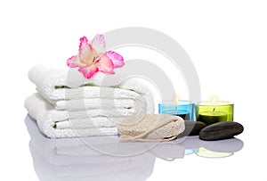 Pink gladiola, towel, candles and river stones