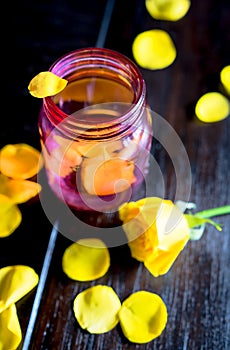 Pink glass jar with yellow rose petals