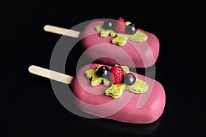 Pink glazed berry gelato ice cream on stick with raspberry, pistachio sponge and black currants