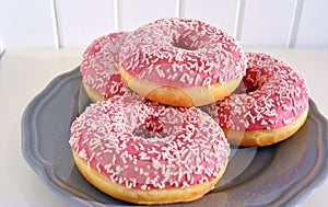 Pink glazed donuts on plate Wooden planks background