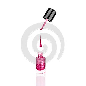 Pink glittering nail polish glass bottle, brush, flowing drop white background isolated closeup, open red sequin varnish, bright