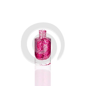 Pink glittering nail polish in glass bottle on white background isolated closeup, opened red sequin varnish, bright shiny magenta