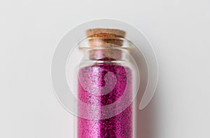 Pink glitters in bottle over white background