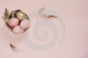Pink and Gold Easter Eggs in a Bowl. Pastel Easter Concept with Eggs and Feathers. Punchy Pastels. Copy Space