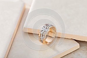 Pink gold and white gold ornament ring with diamond on beige tile background