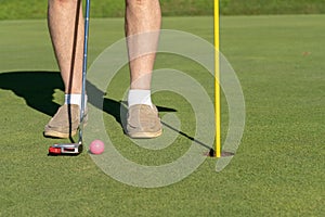 Pink golf ball by flag and hole on putting green