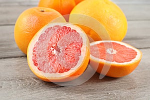 Pink grapefruit cut to half on wood desk, with whole citruses in