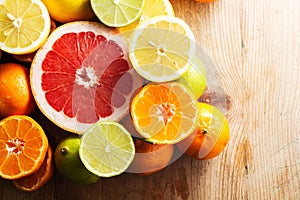 Pink grapefruit and other citrus fruit against wooden background