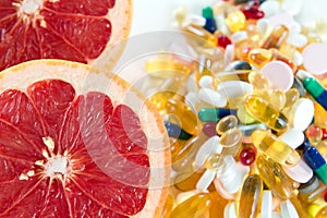 Pink grapefruit and pills, vitamin supplements on white background, healthy diet concept