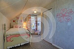 Pink and green girl`s attic bedroom with sloped ceiling