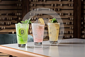 Pink, green and yellow lemonade drinks with ice on the table at restaurant