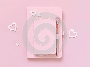 Pink hardcover notebooks, decorative gemstone pen and hearts on light pink top view