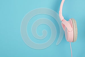 Pink headphones on blue background. Podcast, music, audiobook concept in minimal pop color style