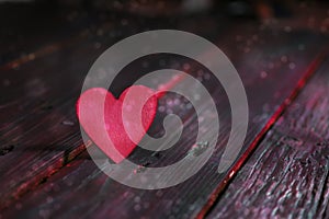 Pink heart on dark rustic wooden planks, flashy love concept for valentines, mother`s day, father`s day or birthday, copy space,