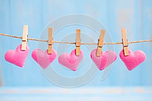 Pink heart shape decoration hanging on line with copy space for text on blue wooden background. Love, Wedding, Romantic and Happy