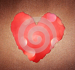 Pink heart shape made from torn paper over glitter boke soft lights.
